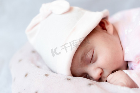 童年、护理、母性、健康概念 — 特写镜头，戴着粉色帽子的小平安平静的新生女婴睡觉休息，躺在柔软温暖的毯子枕窝上，闭上眼睛，睡个小觉