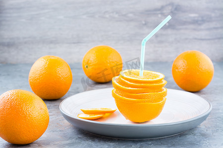 饮料吸管摄影照片_一堆新鲜的橙子片和一根饮料吸管。