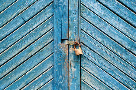 风化复古蓝色木门上的旧挂锁。
