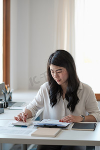 肖像亚洲女商人使用计算器手指图讨论和分析数据图表和图表。企业财务和会计概念