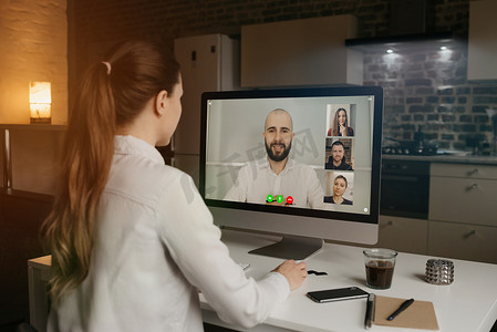 一体机电脑摄影照片_一位女士在电脑视频会议上与同事交谈的后视图。