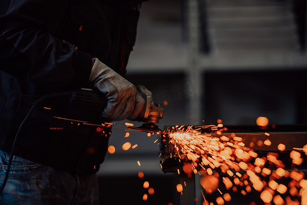 重工业工程工厂内部与产业工人使用角磨机和切割金属管。