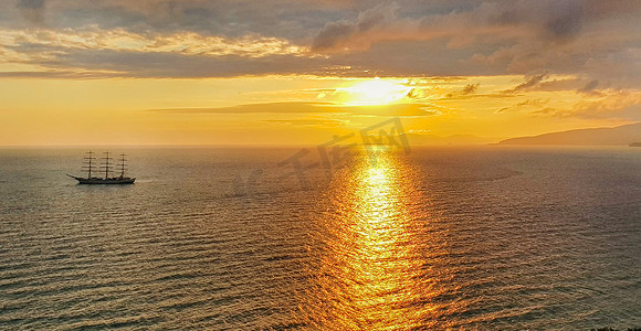 海上浪漫的金色日落，山色和橙色云彩背景下的游艇，这是一个温暖宁静的夜晚的平静场景