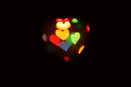 黑暗中一颗心形状的模糊灯光背景。 