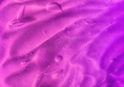透明发光气泡摄影照片_橙色背景上带有气泡和波浪的透明紫色凝胶的纹理