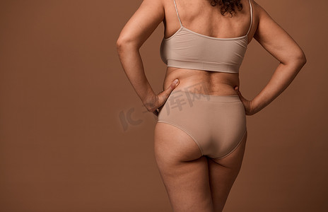 有缺陷摄影照片_女性身体的后视图，在米色背景上隔离有缺陷和缺陷，并带有复制广告空间。