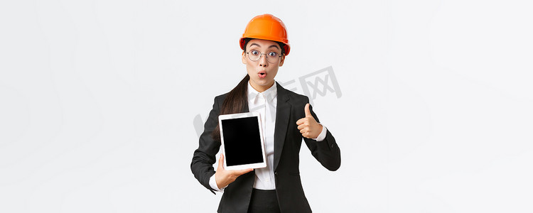 印象深刻和兴奋的亚洲女工程师、穿着西装和安全帽的工业技术人员竖起大拇指和数字平板电脑屏幕，表情惊讶，对利润图做出反应