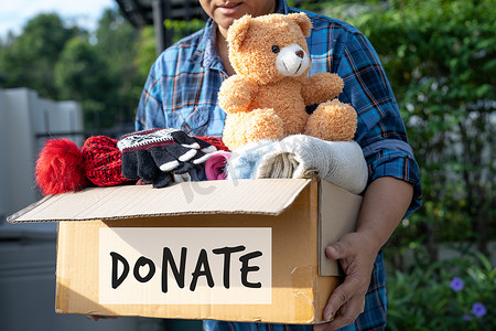 穷人摄影照片_在家中拿着装有旧衣服和娃娃的衣物捐赠箱，以支持对世界上穷人的帮助。