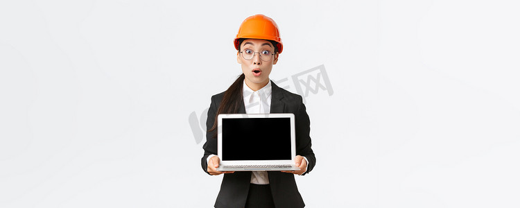 印象深刻和兴奋的亚洲女工程师在图表上显示出惊人的结果，戴安全帽和西装的工业技术人员显示笔记本电脑屏幕，表情惊讶，白色背景