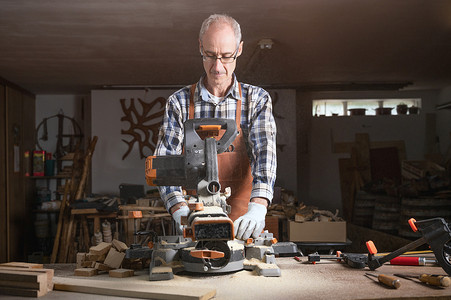 木匠正在木工车间用电动圆锯机锯切木板。