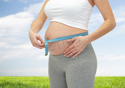 肚子控制摄影照片_孕妇测量肚子的特写