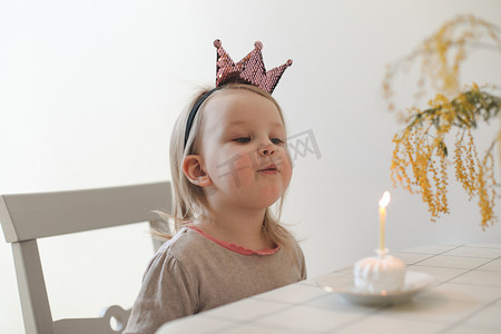 可爱的小女孩吹灭家里生日蛋糕上的蜡烛。