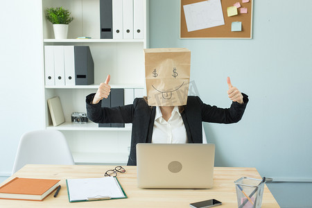 疯狂工作摄影照片_商业、情感和金钱概念 — 办公室疯狂女人把一个画着滑稽面孔的包裹放在头上。