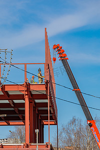 起重机梁摄影照片_建筑工人用起重机固定铁梁。