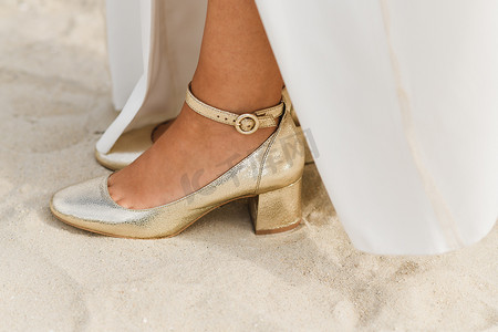 海岸白色沙滩上新娘金色闪亮的鞋子