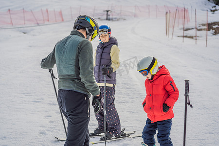 安全指导员摄影照片_妈妈和儿子正在教练的指导下学习滑雪。