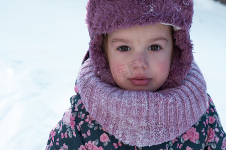 冬天、家庭、童年概念 — 戴着粉色帽子的正宗学龄前未成年 3-4 岁女孩的特写肖像，在雪天结霜的天气里看着相机摆出微笑。