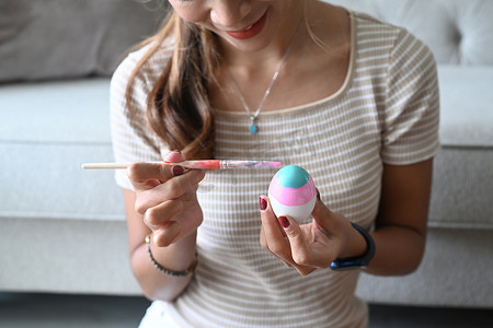 水彩女子摄影照片_年轻女子喜欢在复活节的鸡蛋上画水彩。