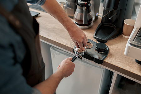 咖啡师捣固研磨咖啡以制作浓缩咖啡的特写