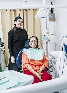 办公室里有病人对着镜头微笑的牙医、满意的牙医和病人对着镜头微笑、满意的牙医和病人的概念