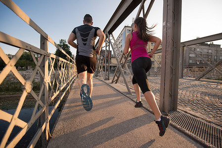 年轻夫妇慢跑过城市的桥