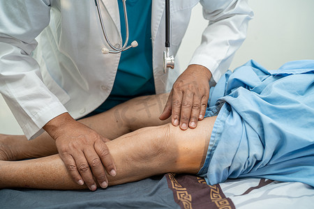 护士按摩摄影照片_亚洲医生物理治疗师在骨科医疗诊所护士医院检查、按摩和治疗老年患者的膝盖和腿部。