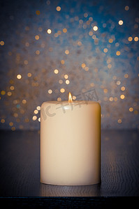 火焰蓝摄影照片_蓝色散景背景中木桌上有火焰的蜡烛