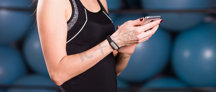 手机app生活摄影照片_女性在健身房使用手机和健身追踪器的特写