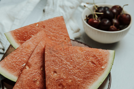 西瓜简约摄影照片_一堆夏季和新鲜水果在简约的白色桌子上，西瓜和樱桃，健康和健康食品概念，美味，质感，复制空间