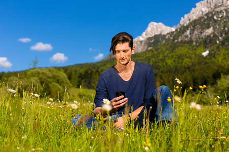 享受旅行摄影照片_拿着电话的男人坐在山里