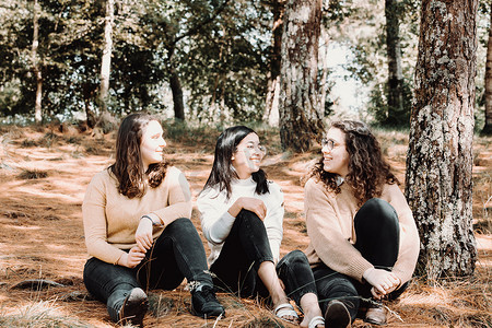 三名年轻女学生在阳光明媚的日子里在森林里聊天，友谊、爱和关怀的概念