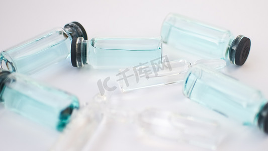 小瓶疫苗、白色背景上透明蓝色液体的玻璃安瓿顶视图、全球疫苗接种概念