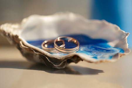 在海滩婚礼上，桌上贝壳中的结婚戒指与婚礼装饰的特写视图
