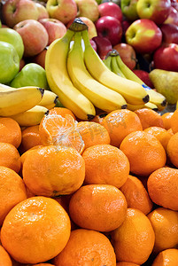 成熟的橙子、香蕉和苹果躺在市场柜台上出售。