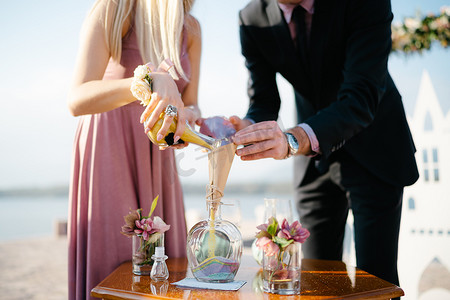 新郎和新娘将彩色沙子分层倒入玻璃罐中