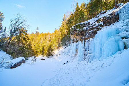 日落时悬崖上的雪和冰蓝色冰冻瀑布