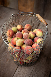收获桃子摄影照片_深色木质乡村背景的篮子里的新鲜桃子，顶视图。