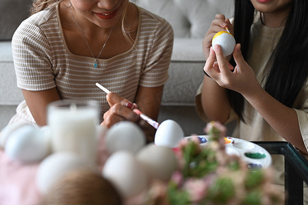 母亲和女儿在复活节前一起度过时光，画色彩缤纷的复活节彩蛋。