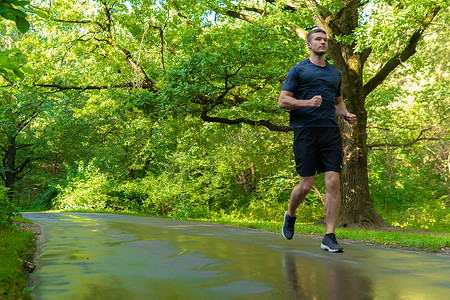 一名男子运动员在公园户外跑步，在森林周围，橡树绿草年轻持久的运动运动员健康跑步锻炼，锻炼慢跑者训练健康慢跑，外面的树林。