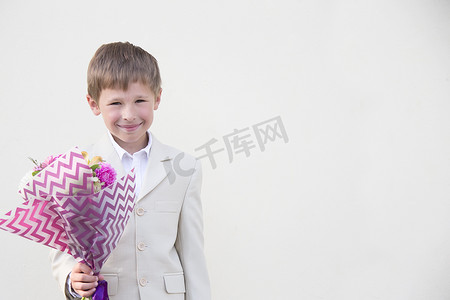 一年级男孩穿着一套漂亮的西装，手里拿着一束鲜花