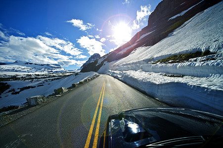 蒙大拿州摄影照片_山脊公路 - 美国蒙大拿州冰川国家公园的向阳之路 雪原和岩石。