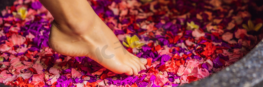 花瓣摄影照片_有魅力的年轻女子在沐浴着热带花卉和芳香油的花瓣。