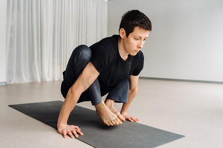 一名身穿黑色T恤的男子躺在健身房里做伸展运动
