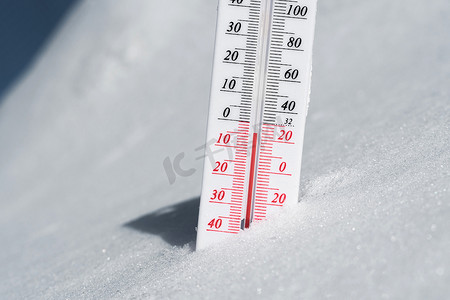 气候分析摄影照片_温度计位于雪上，在蓝天的寒冷天气中显示负温度。空气和环境温度低的气象条件。气候变化和全球变暖