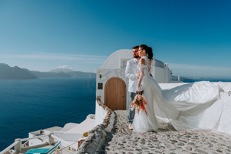 美丽的新娘和新郎在希腊圣托里尼岛的夏季婚礼上