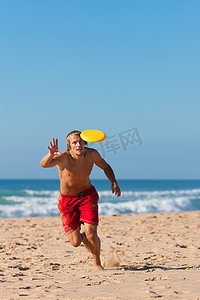 沙滩上玩飞盘的男人