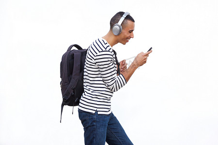 走路听音乐摄影照片_年轻人带着手机走路，戴着耳机听音乐