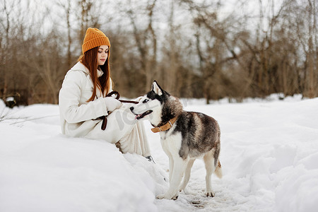 快乐的年轻女人冬装在雪地里遛狗