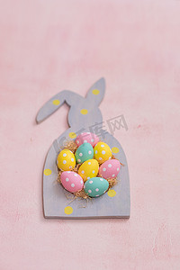粉色混凝土背景兔形框架中的彩色圆点复活节彩蛋