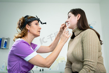专业女医生耳鼻喉科医生在现代医院用耳镜进行鼻子检查。